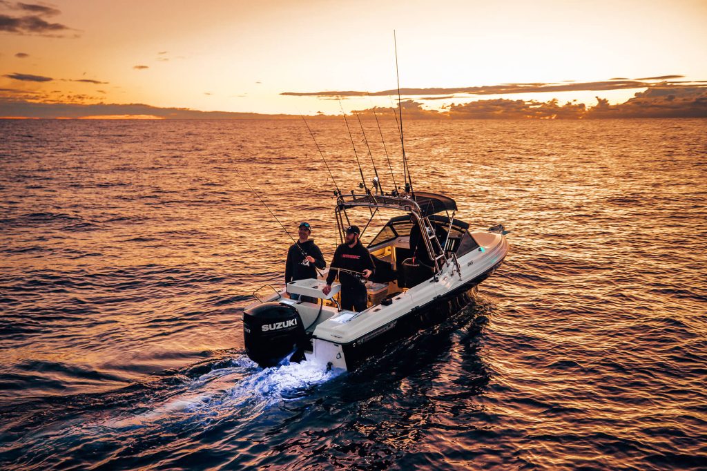 Two men on a fishing boat at sunset.